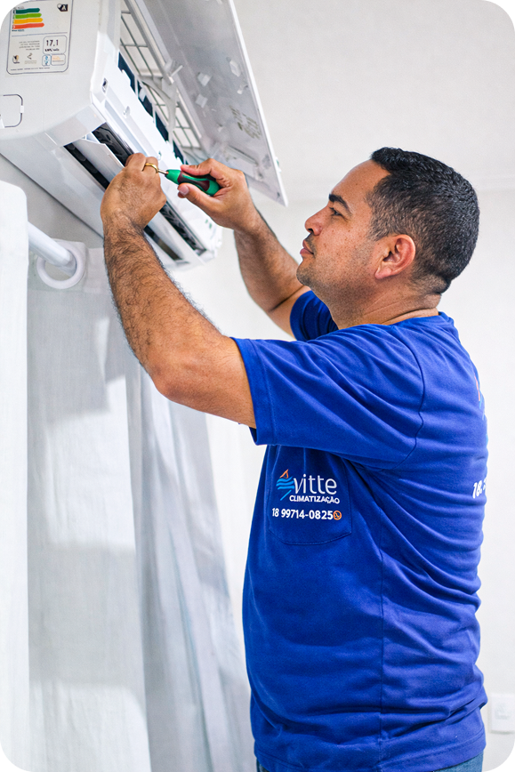 Diego, da Vitte Climatização, fazendo a manutenção de um ar-condicionado split
